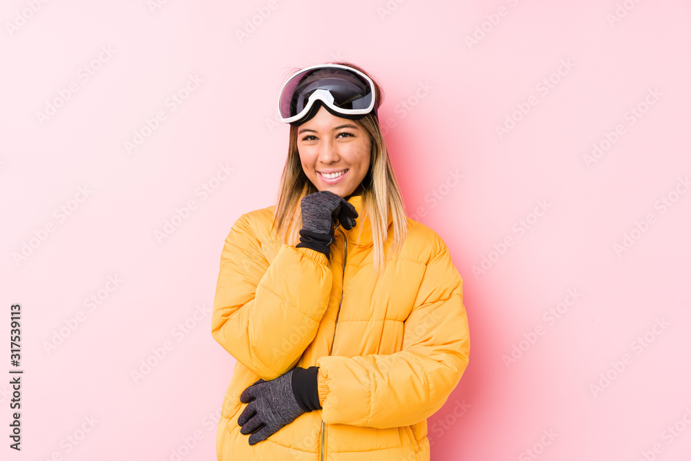 Young caucasian woman wearing a ski clothes in a pink background smiling happy and confident, touching chin with hand.