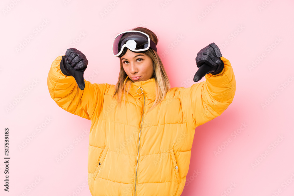 Young caucasian woman wearing a ski clothes in a pink background showing thumb down and expressing dislike. Young caucasian woman wearing a ski clothes in a pink background showing thumb down and expressing dislike.