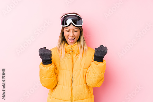 Young caucasian woman wearing a ski clothes in a pink background cheering carefree and excited. Victory concept.