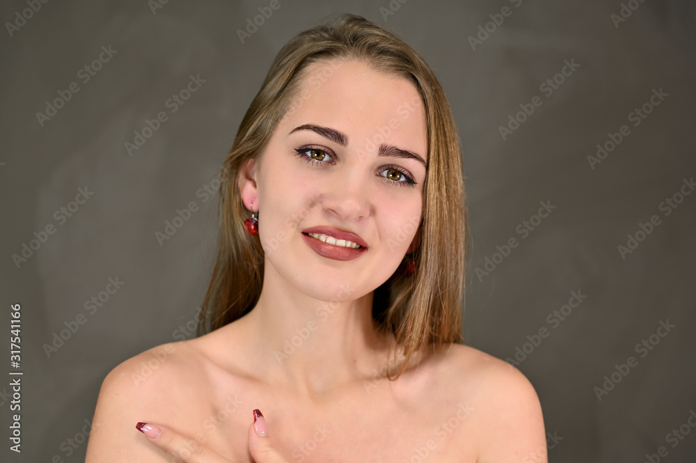 Universal concept female portrait on a gray background. Horizontal beauty photo of a pretty smiling girl with long hair and great makeup and good skin. Universal concept female portrait on a gray background. Horizontal beauty photo of a pretty smiling girl with long hair and great makeup and good skin.