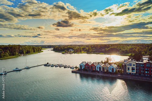 Aerial view of colorful boats near wooden berth and buildings in the countryside of Finland at sunset photo