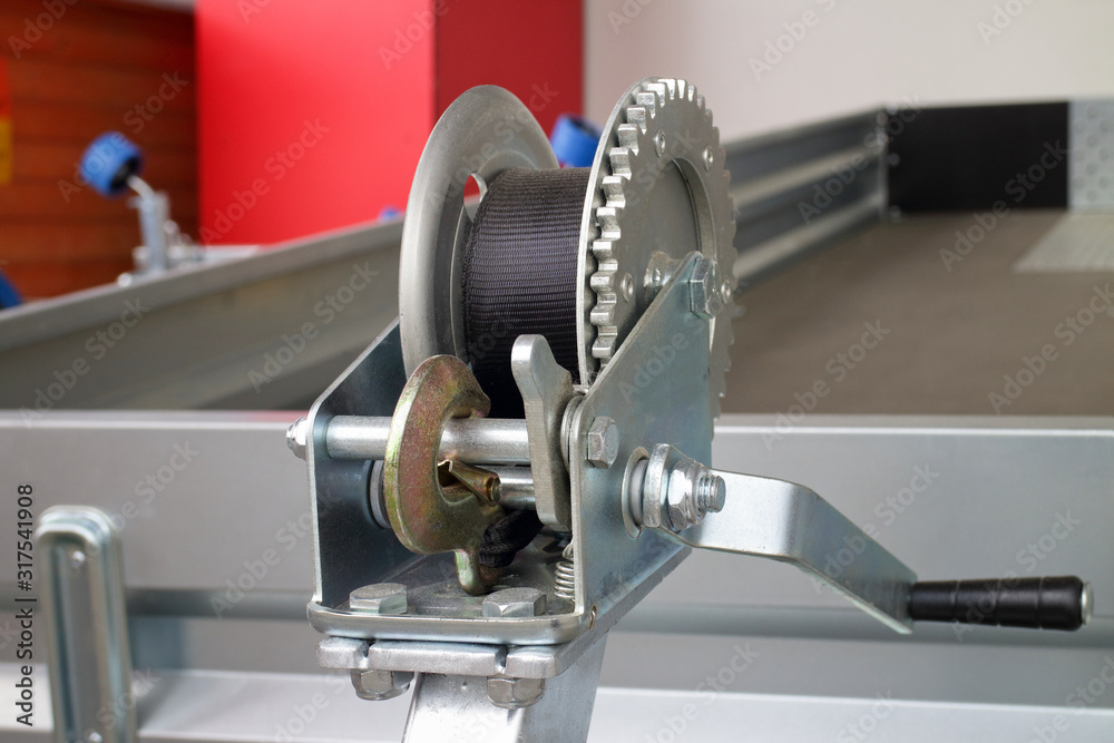 detailed photo of the construction of a small metal mechanical wire rope winch with a stainless steel hook