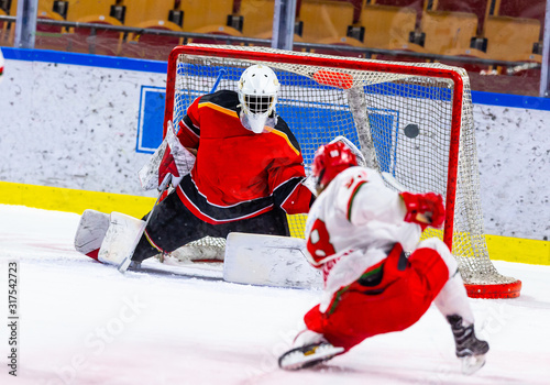 Photography Ice hockey player tries to score with a slap shot and one knee down on the ice