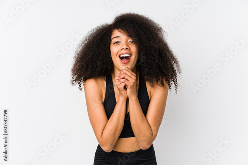 Young african american sporty woman praying for luck, amazed and opening mouth looking to front.