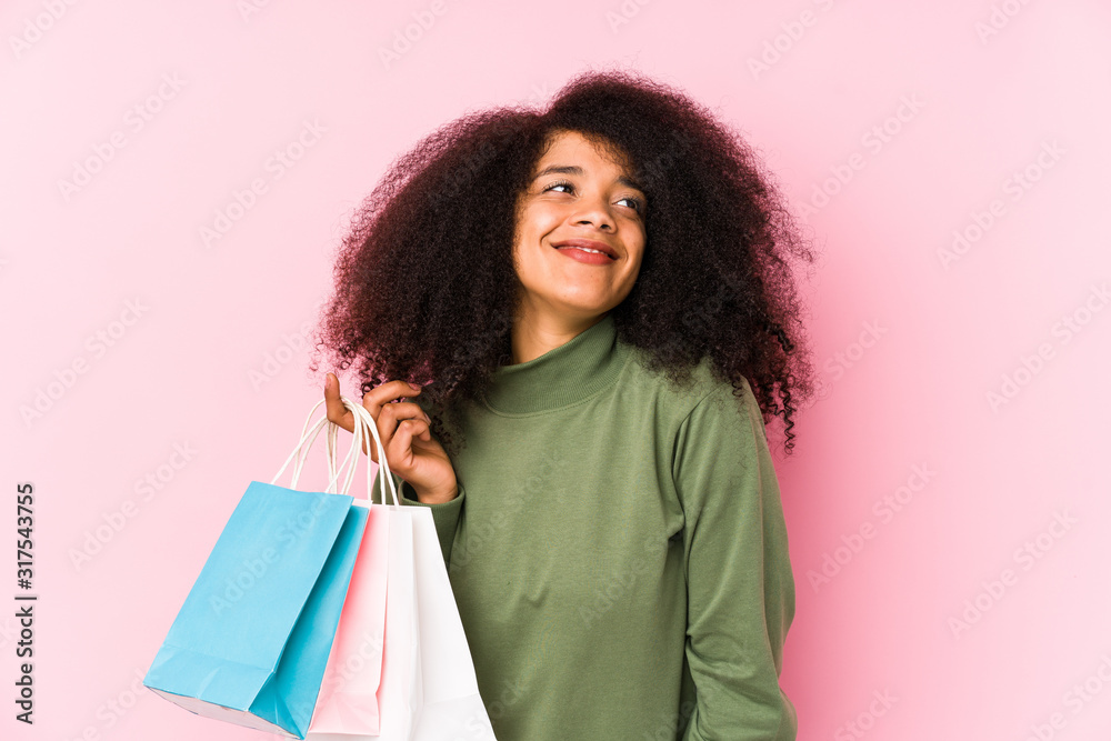Young afro woman shopping isolated Young afro woman buying isolaYoung afro woman holding a roses isolated dreaming of achieving goals and purposes< mixto >