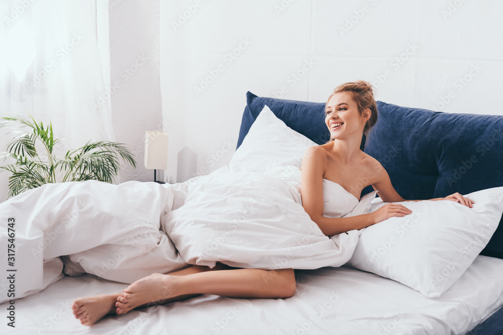 beautiful smiling woman lying in sheets on bed in morning beautiful smiling woman lying in sheets on bed in morning