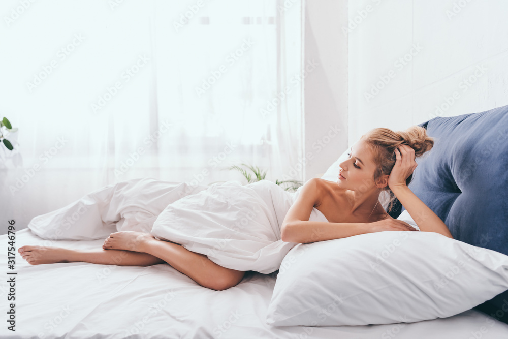 beautiful young woman lying in sheets on bed in morning beautiful young woman lying in sheets on bed in morning