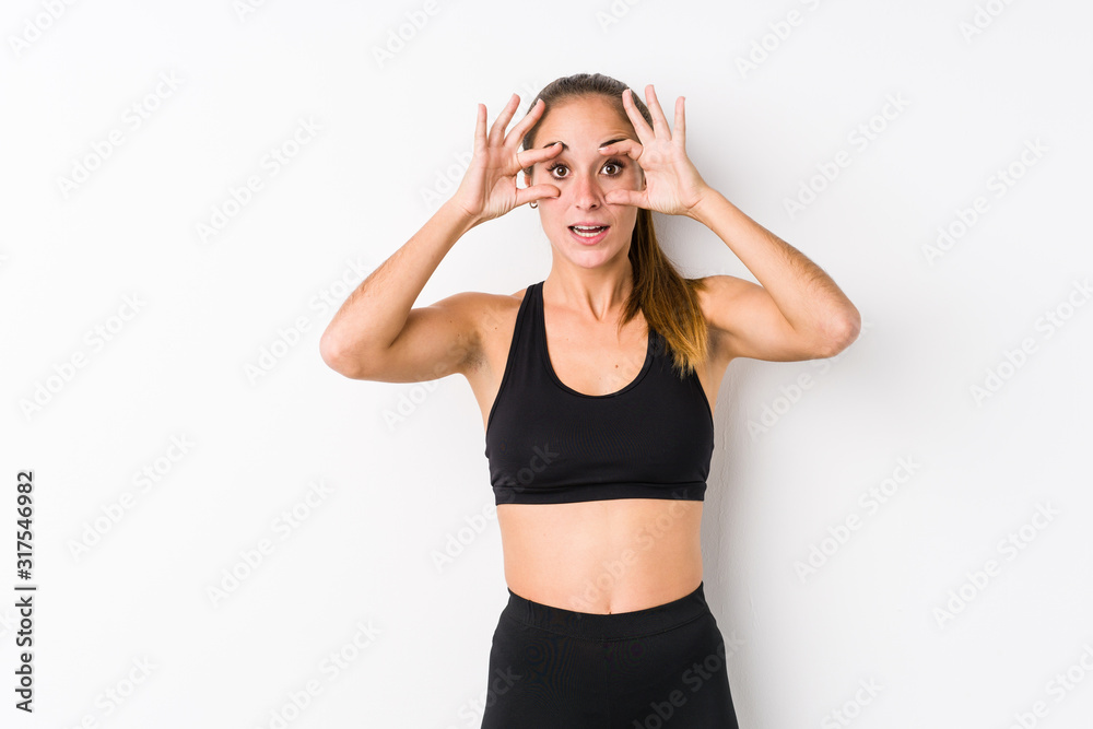 Young caucasian fitness woman posing in a white background keeping eyes opened to find a success opportunity. Young caucasian fitness woman posing in a white background keeping eyes opened to find a success opportunity.