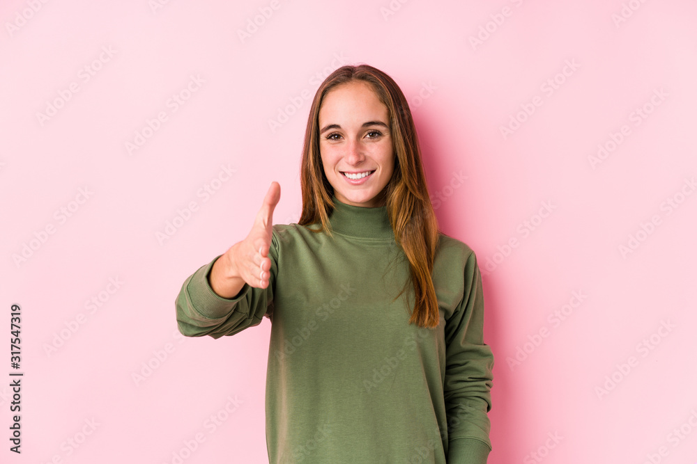 Young caucasian woman posing isolated stretching hand at camera in greeting gesture. Young caucasian woman posing isolated stretching hand at camera in greeting gesture.