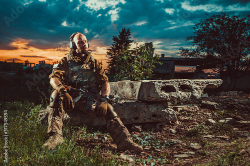 American soldier with the M4 rifle is having a rest. Sunset on the background.