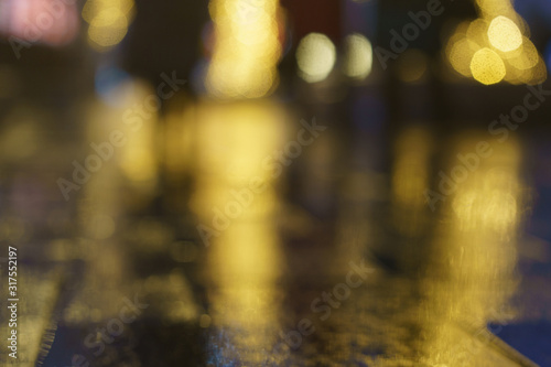 Defocused photography of colorful street lights in night. Impressionism style. Gold lights with black background. Silhouettes of people. Suitable as background for miracle creative template