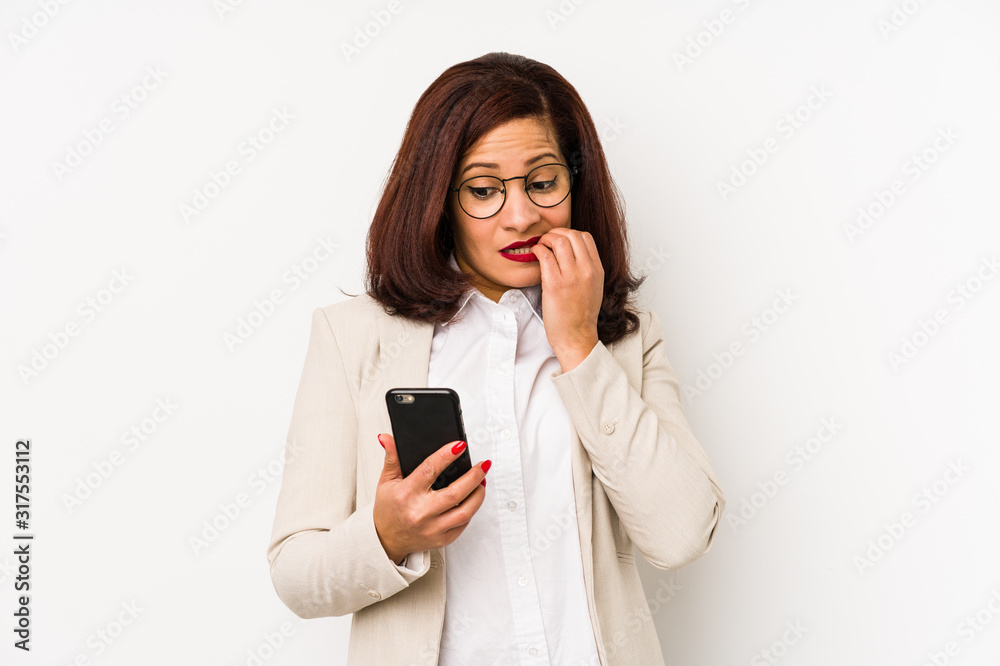 Middle age latin woman holding a mobile phone isolated biting fingernails, nervous and very anxious. Middle age latin woman holding a mobile phone isolated biting fingernails, nervous and very anxious.