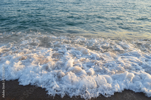 Mediterranean sea at sunset. Waves break on the sandy shore, sea foam. Natural