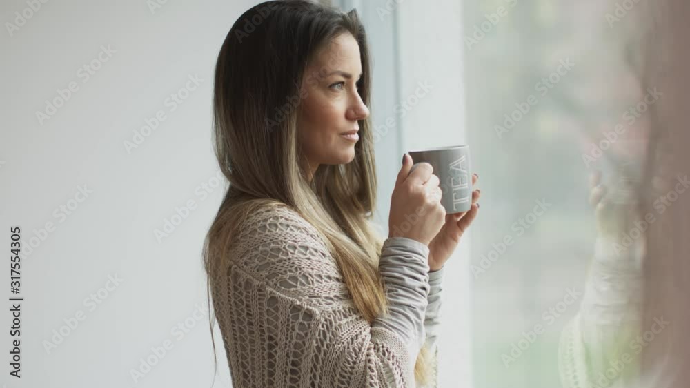 beautiful young woman drinking tea and looking outside. Shot in Slovenia. beautiful young woman drinking tea and looking outside. Shot in Slovenia.