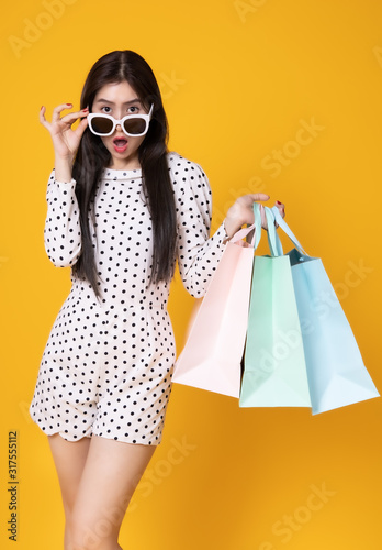 Asian woman in summer casual clothes.She smiling and happy shopping bags. she lovely attractive shine on yellow background.Summer Surprise Sale concept.