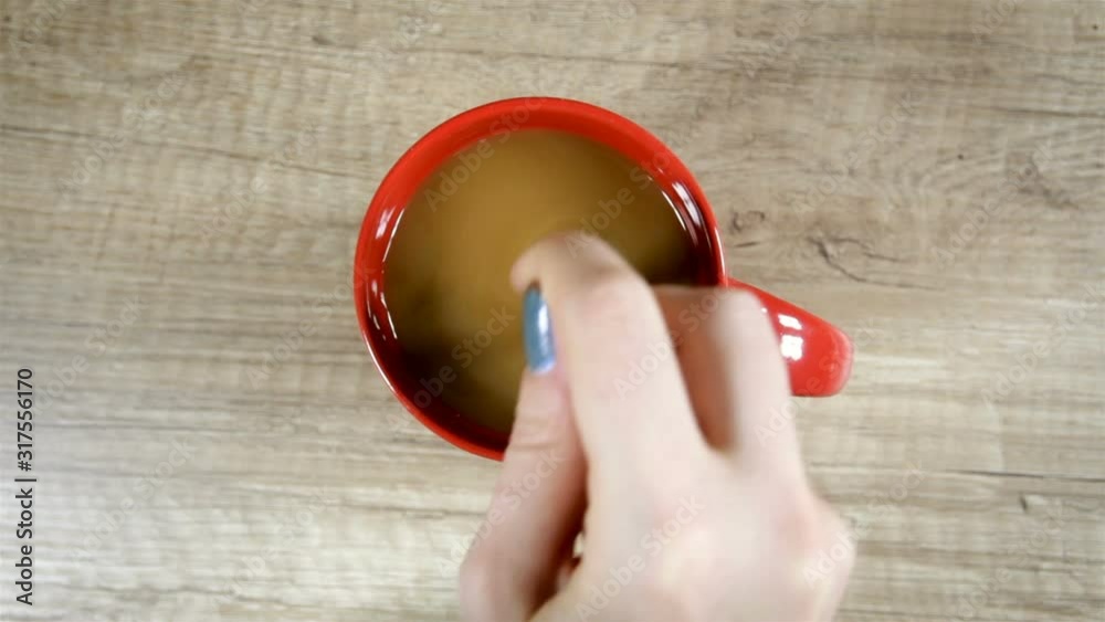 Top view of Person hand steering coffee in a cup with spoon. Young white woman by hands is mixing coffee Top view of Person hand steering coffee in a cup with spoon. Young white woman by hands is mixing coffee