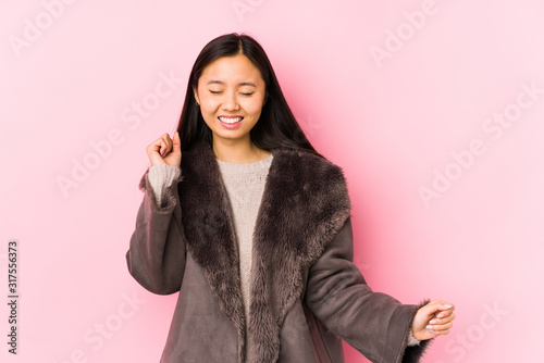 Young chinese woman wearing a coat isolated dancing and having fun.