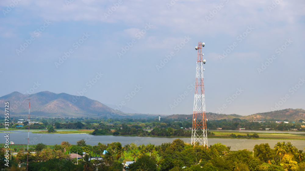 Radio towers, telecommunications tower with mountain range background with warm sunset light casting on clouds, good background for wireless technology.