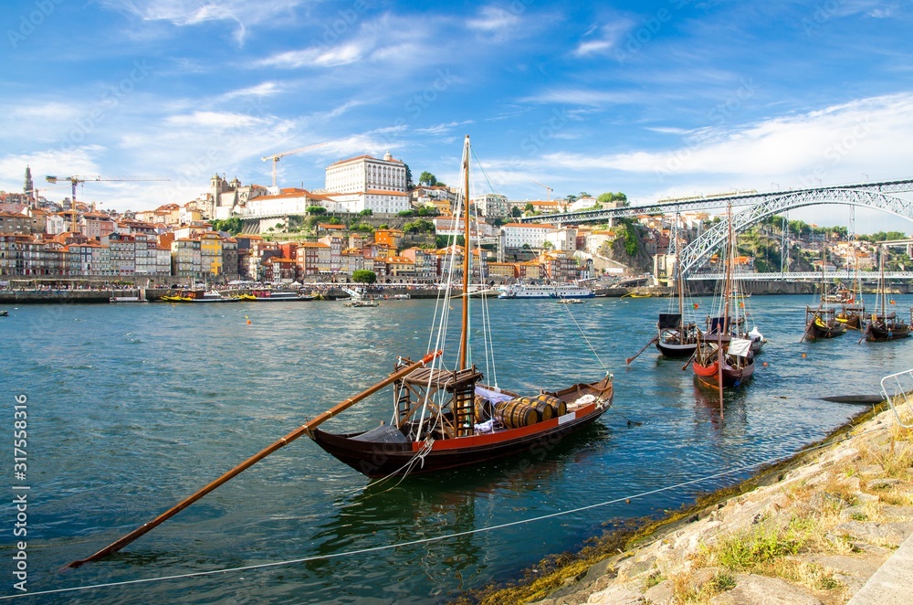 Portugal, city landscape Porto, colored wooden boats with wine port barrels on Douro river, panoramic view of the old town Porto,  The Eiffel Bridge view, Ponte Dom Luis, Porto in summer