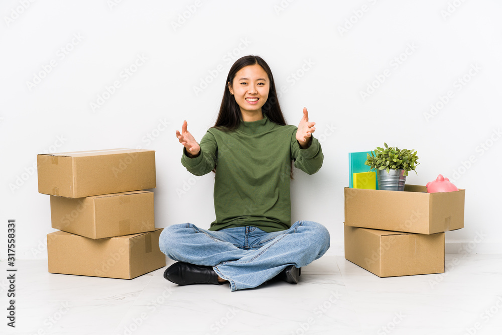 Young chinese woman moving to a new home feels confident giving a hug to the camera. Young chinese woman moving to a new home feels confident giving a hug to the camera.