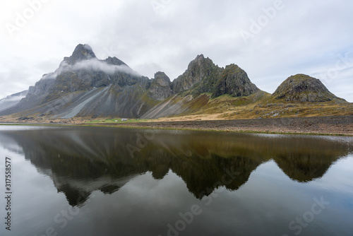 Eystrahorn mountain peaks with fog around and beautiful reflections in the calm lake. Road trip and destination concept. © Jon Anders Wiken