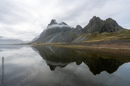 Eystrahorn mountain peaks are reflecting in the calm water on the south coast of Iceland. Ring road, explorer and backpacking concept. photo