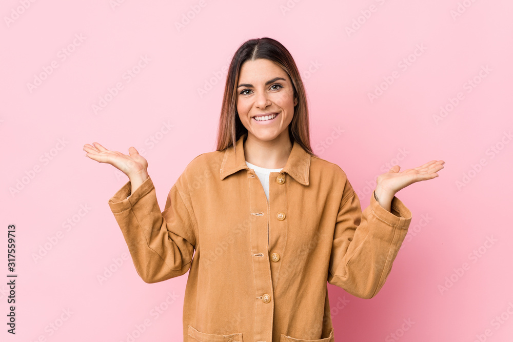 Young caucasian woman isolated makes scale with arms, feels happy and confident. Young caucasian woman isolated makes scale with arms, feels happy and confident.