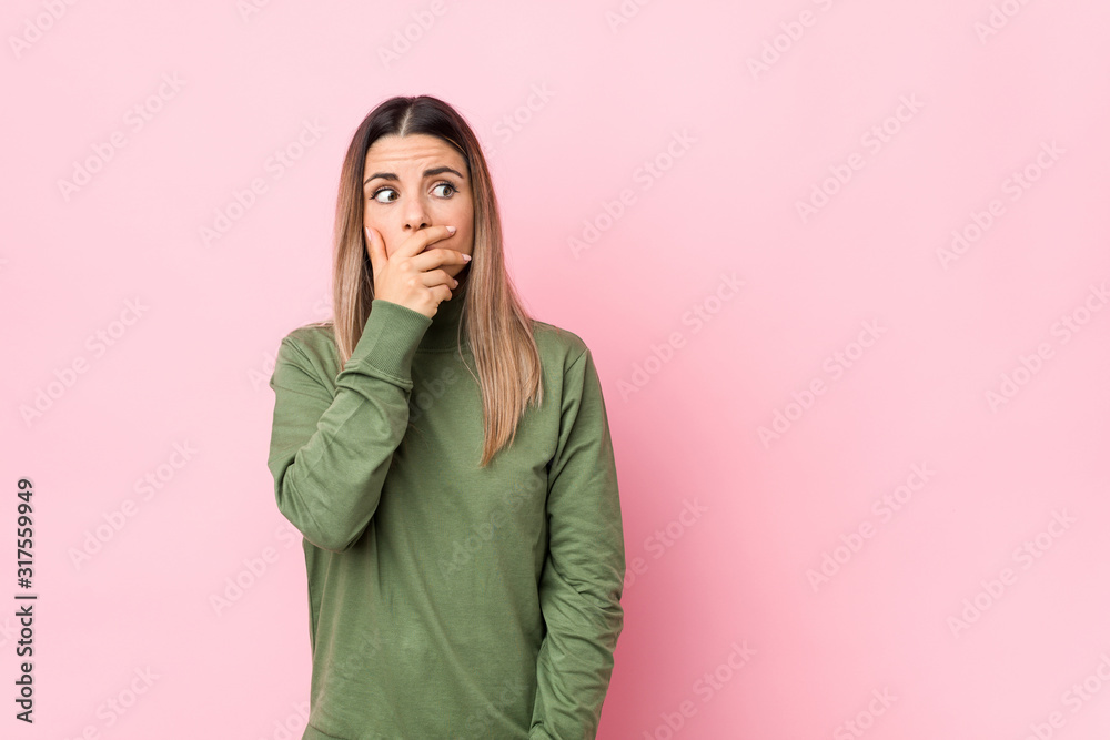 Young caucasian woman isolated thoughtful looking to a copy space covering mouth with hand. Young caucasian woman isolated thoughtful looking to a copy space covering mouth with hand.