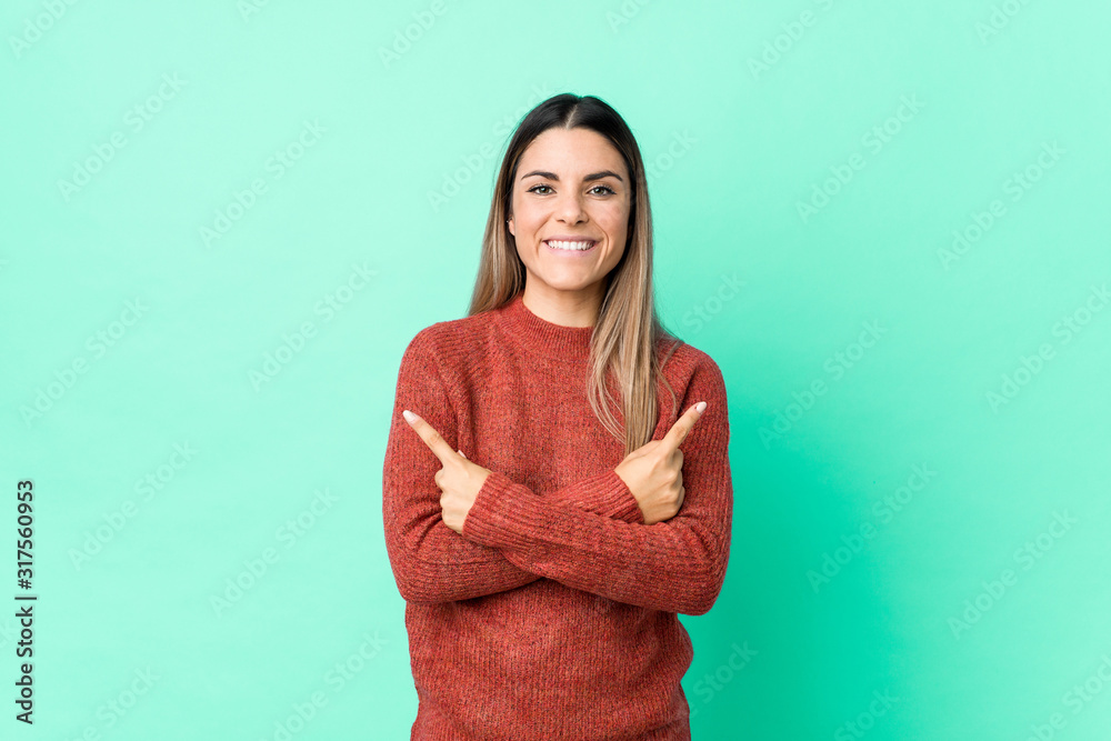 Obraz premium Young caucasian woman isolated points sideways, is trying to choose between two options.