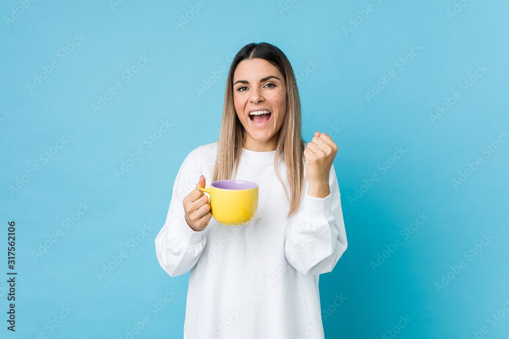 Young caucasian woman holding a coffee cup cheering carefree and excited. Victory concept.