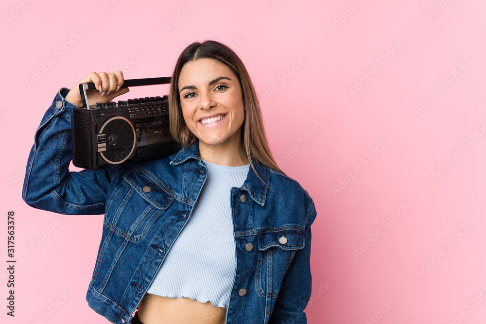 Young caucasian woman holding a guetto blaster smiling confident with crossed arms. Young caucasian woman holding a guetto blaster smiling confident with crossed arms.