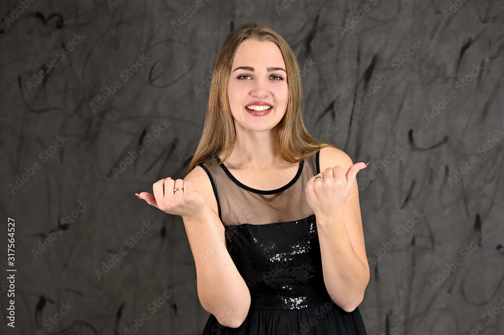 Universal concept of horizontal female portrait on gray alternative background. A photo of a pretty smiling girl with long hair and excellent make-up in a black dress stands in different poses. Universal concept of horizontal female portrait on gray alternative background. A photo of a pretty smiling girl with long hair and excellent make-up in a black dress stands in different poses.