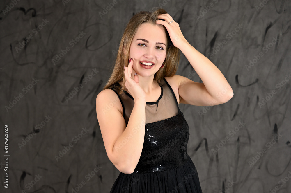 Universal concept of horizontal female portrait on gray alternative background. A photo of a pretty smiling girl with long hair and excellent make-up in a black dress stands in different poses. Universal concept of horizontal female portrait on gray alternative background. A photo of a pretty smiling girl with long hair and excellent make-up in a black dress stands in different poses.