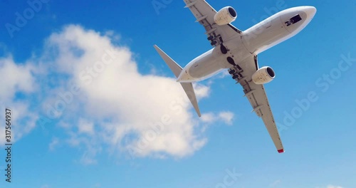 Airplane at take off seen from the bottom. Airplane in the blue sky with white clouds. Commercial plane in a flight close up, bottom view.