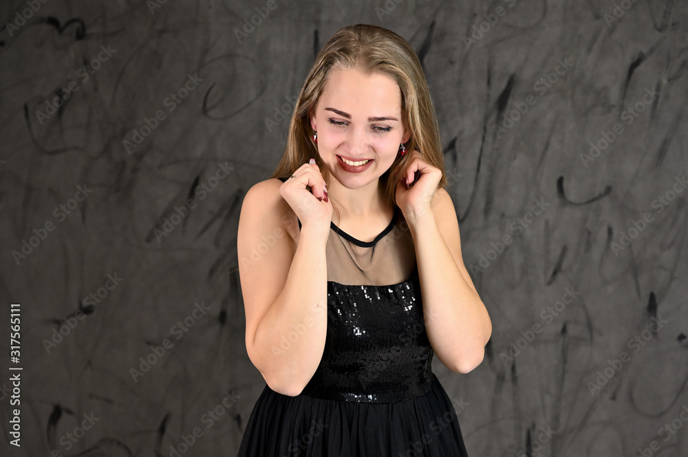 Universal concept of horizontal female portrait on gray alternative background. A photo of a pretty smiling girl with long hair and excellent make-up in a black dress stands in different poses. Universal concept of horizontal female portrait on gray alternative background. A photo of a pretty smiling girl with long hair and excellent make-up in a black dress stands in different poses.