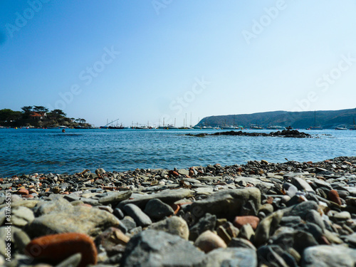 Rocas en la playa de Cadaqués con barcos en el mar azul