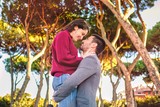Young couple in love having fun at the park and enjoy in beautiful nature with mediterranean trees in soft blurred background - valentine deep emotion and love feelings concept - warm color image