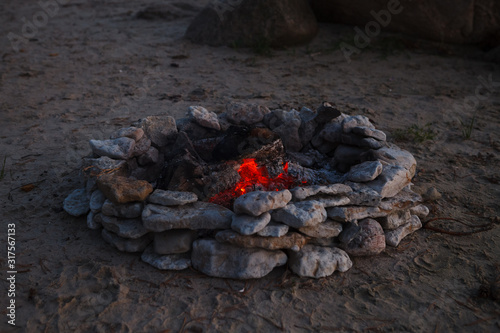 Bonfire or campfire in stone pit of pebbles on the sandy beach. Late summer evening. photo