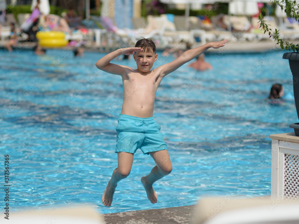 Boy having fun making fantastic jump into swimming pool on summer vacations.