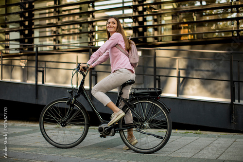 Young woman riding e bike in urban enviroment photo