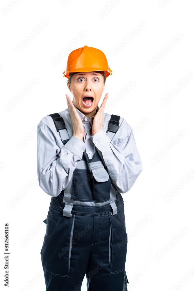 Young woman in uniform and helmet, worker, foreman surprised and scared. the specialist opened his mouth in surprise. the girl is terrified. isolated Young woman in uniform and helmet, worker, foreman surprised and scared. the specialist opened his mouth in surprise. the girl is terrified. isolated