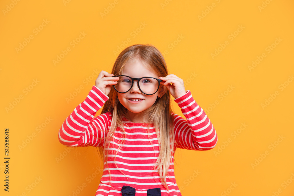 Portrait of young smiling girl wearing glasses on yellow background Portrait of young smiling girl wearing glasses on yellow background