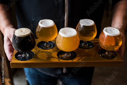 Hands holding a flight of various craft beers