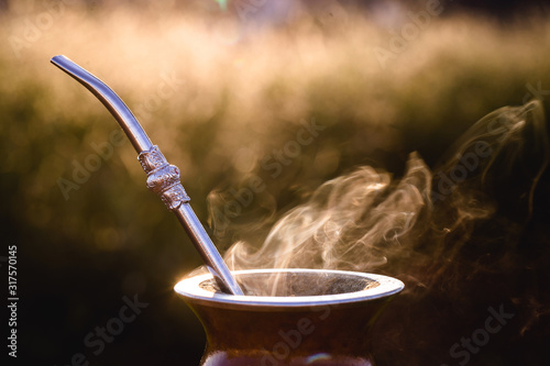 mate bowl, outdoors. Yerba mate typical of Argentina, Brazil and Uruguay. Mountain scenery in the background. It consists of a gourd, a pump, ground yerba mate and warm water. photo