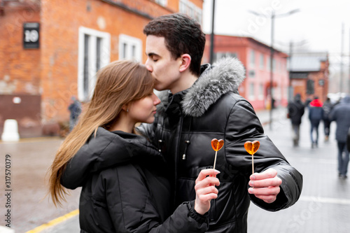 Young couple in love on the street with heart shaped lollipops.