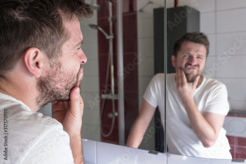 Man check condition of his skin in mirror reflection at the bathroom