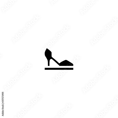 Female shoe with high heel on pedestal. Elegant black slipper with spike heel on while background.