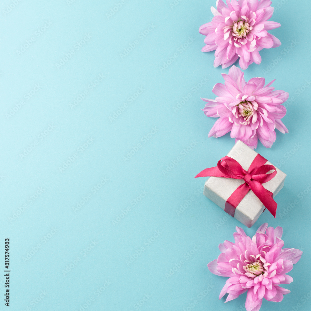 Pink flowers and gift box on blue background. Romantic background for Valentine Day, Mothers Day or Birthday. Top view. Space for text. 