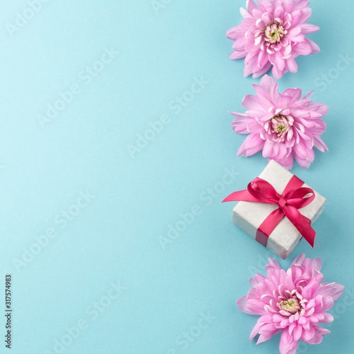 Pink flowers and gift box on blue background. Romantic background for Valentine Day, Mothers Day or Birthday. Top view. Space for text. 