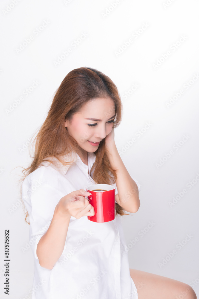 Asian woman portrait with perfect skin and wearing a white shirt in happiness holding red coffee cup isolated on white background.